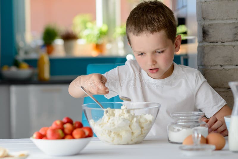 Child adding sugar to cottage cheese in a bowl. stock image