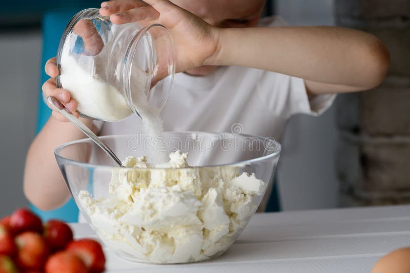 Child adding sugar to cottage cheese in a bowl. royalty free stock photography