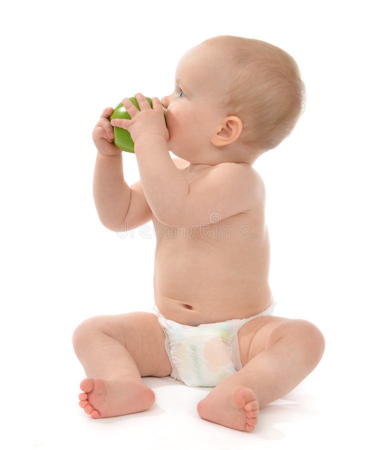 Child baby boy sitting in diaper and eating green apple