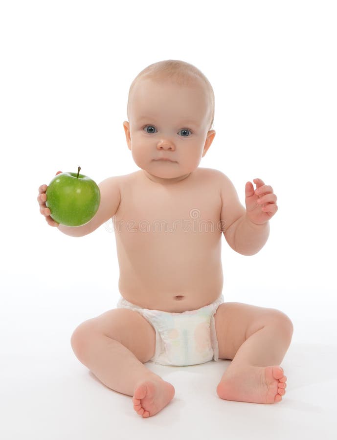 Child baby girl toddler sitting in diaper and eating green apple