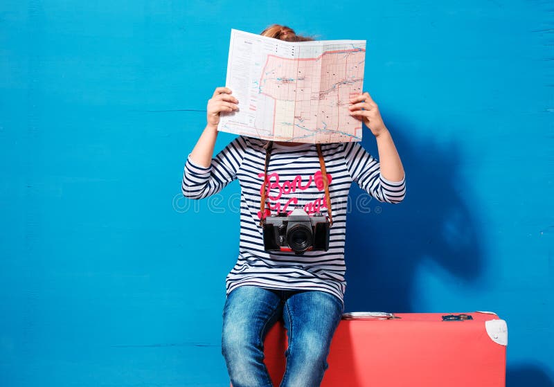 Child blonde girl with pink vintage suitcase and city map ready for summer vacation. Travel and adventure concept