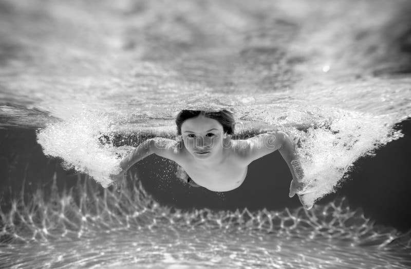 Child boy swim under water in sea. Kid swimming in pool underwater. Happy boy swims in sea underwater, active kid