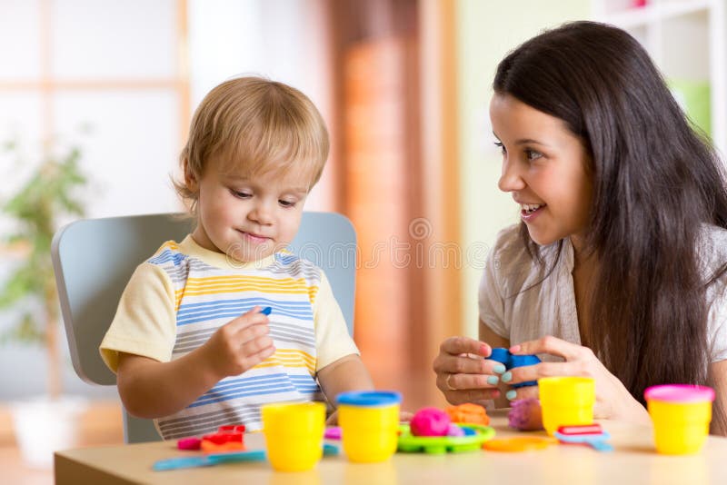 Child boy and woman play colorful clay toy at