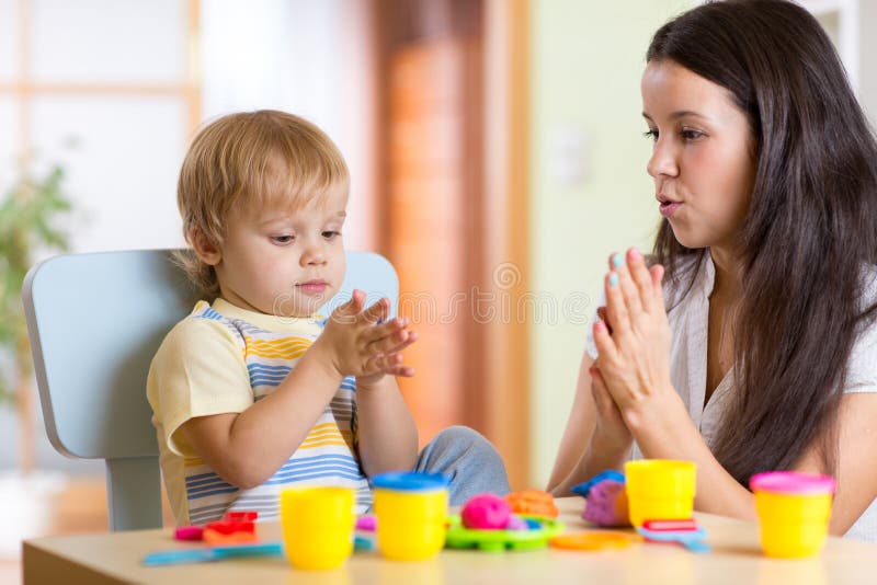 Child boy and woman playing colorful clay toy at