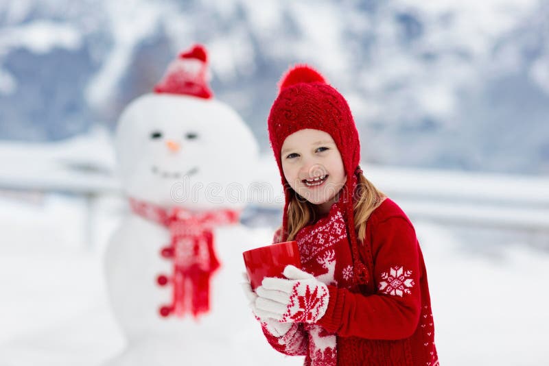 Child building snowman. Kids build snow man. Boy and girl playing outdoors on snowy winter day. Outdoor family fun on Christmas
