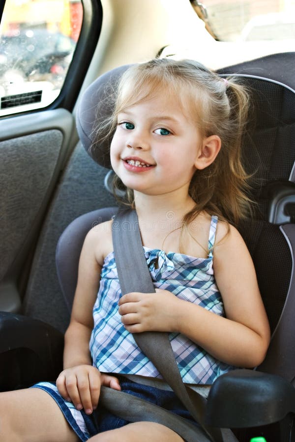 Bambina in un seggiolino per auto e sorridendo alla telecamera.