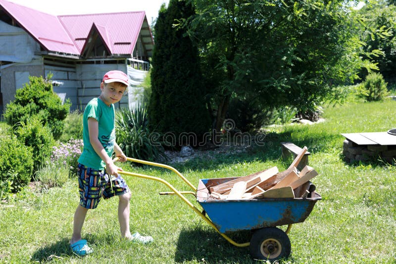Child carrying firewood in wheelbarrow royalty free stock images