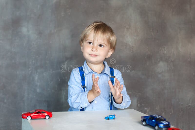 The child claps his hands. Portrait of a cute little boy playing with cars. Preschool boy playing with toy cars in kindergarten. E