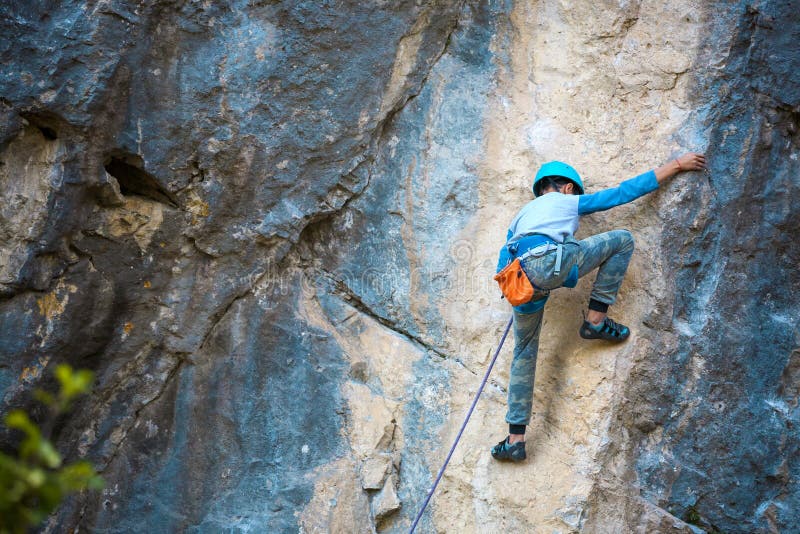 A child climber climbs on a rock