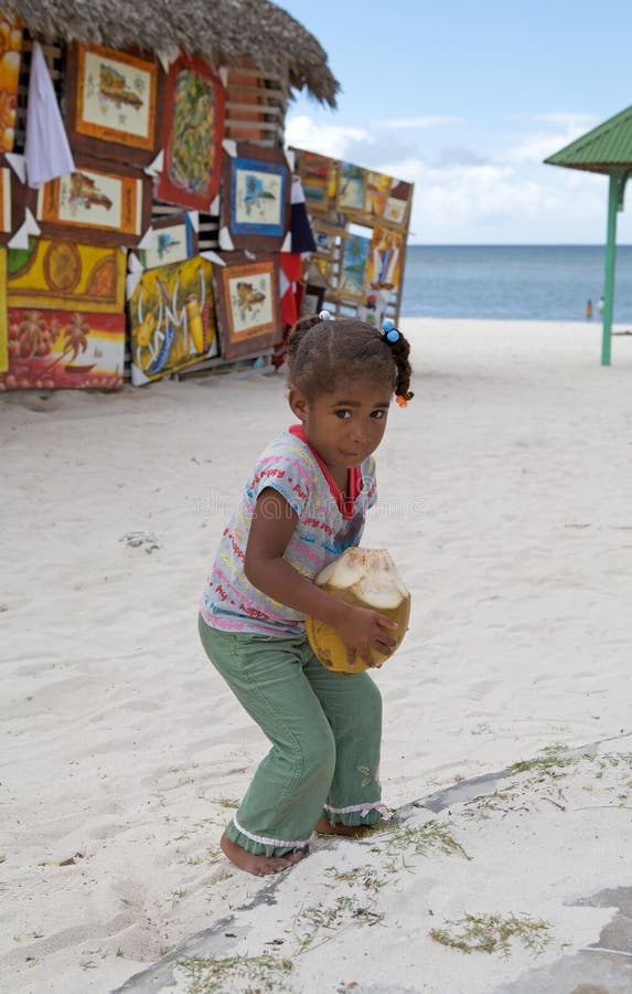 Child with coconut fruit at the Saona village, Saona island, with traditional dominican paints in the background. Saona Island is a tropical island located a short distance from the mainland on the south-east tip of the Dominican Republic, Hispaniola island. It is a government protected nature reserve and is part of East National Park. Child with coconut fruit at the Saona village, Saona island, with traditional dominican paints in the background. Saona Island is a tropical island located a short distance from the mainland on the south-east tip of the Dominican Republic, Hispaniola island. It is a government protected nature reserve and is part of East National Park