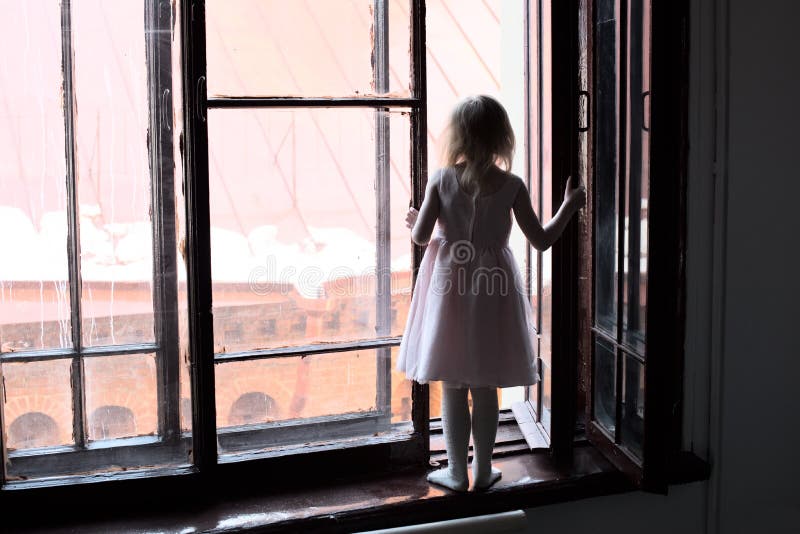 The child is in danger - the girl in the dress is standing on the windowsill