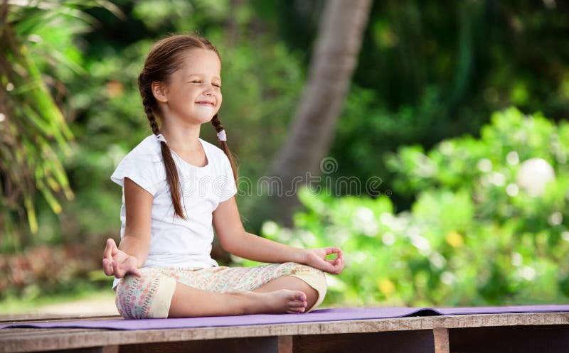 Child doing exercise on platform outdoors. Healthy lifestyle. Yoga girl