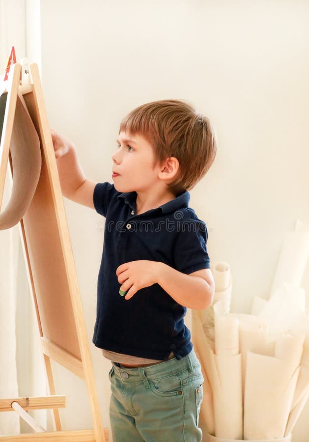 Child is drawing and painting with felt pen on paper of wooden drawing board artist easel for kids and children at home. Childhood royalty free stock image Child is drawing and painting with felt pen on paper of wooden drawing board artist easel for kids and children at home. Childhood royalty free stock image