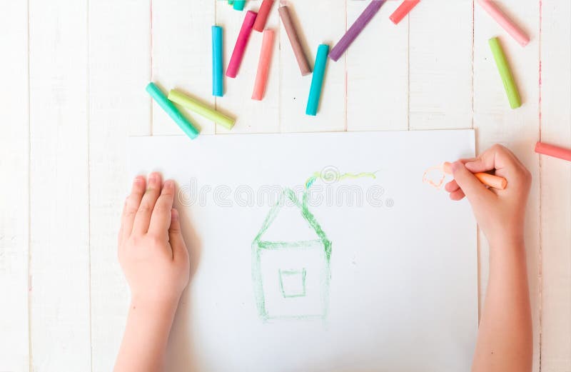 A child draws a house with crayons. House. Multicolored crayons, pastel