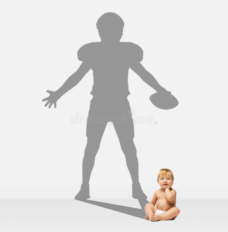 Child dreaming about big and famous future. Conceptual image with boy and drawned shadow of male american football player on gray background background. Childhood, imagination, education concept. Child dreaming about big and famous future. Conceptual image with boy and drawned shadow of male american football player on gray background background. Childhood, imagination, education concept.