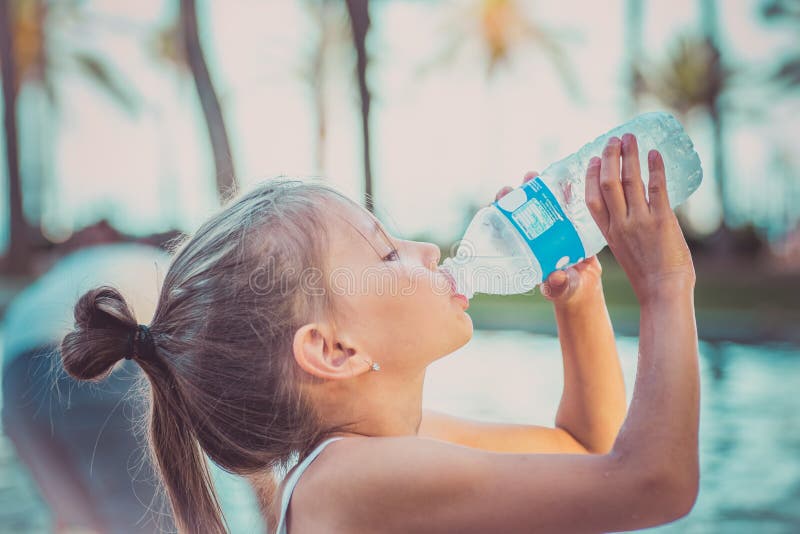 A child is drinking clean water from a bottle. Hot summer day