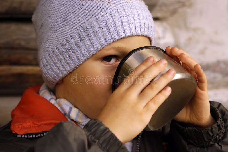Little Boy Holding a Cup of Tea Outdoors. Child Drinks Tea Stock Photo