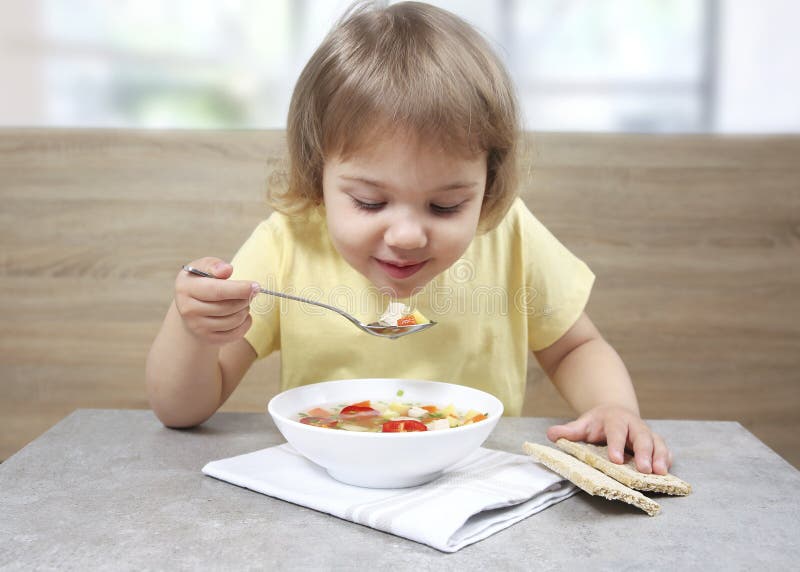 Child eating soup.Caucasian little girl sitting at table and have a meal