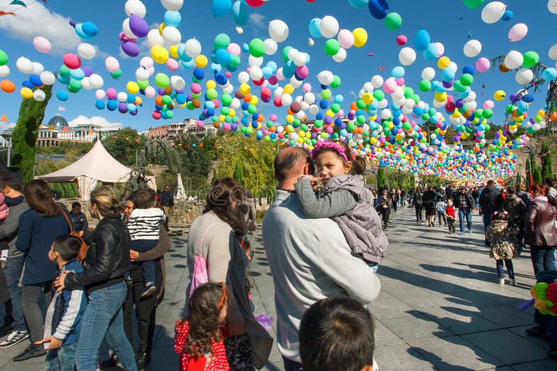 Child on father`s hands having fun with family at city festival Tbilisoba