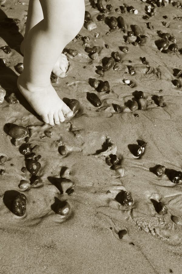 Child feet on beach. toddler with feet in sand with pebbles in monochrome. seaside picture with baby toe or toes. Child feet on beach. toddler with feet in sand with pebbles in monochrome. seaside picture with baby toe or toes
