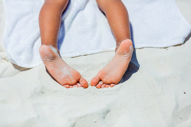 Child feet on beach towel