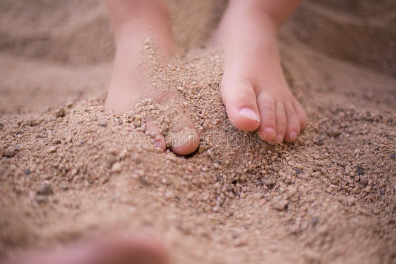 Child feet in sand.