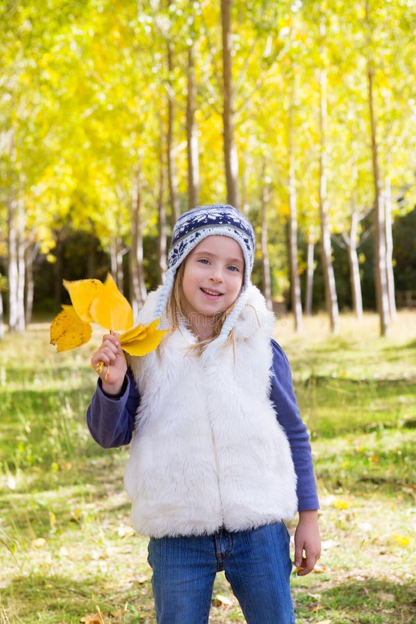 Child girl in autumn poplar forest yellow fall leaves in hand