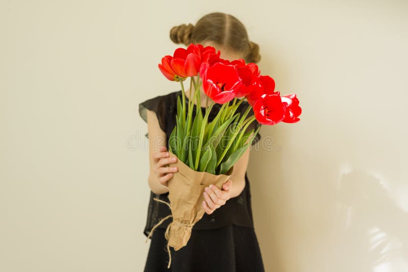 Child girl holding bouquet of red tulips flowers. Gift, surprise, spring family holiday stock photos Child girl holding bouquet of red tulips flowers. Gift, surprise, spring family holiday stock photos