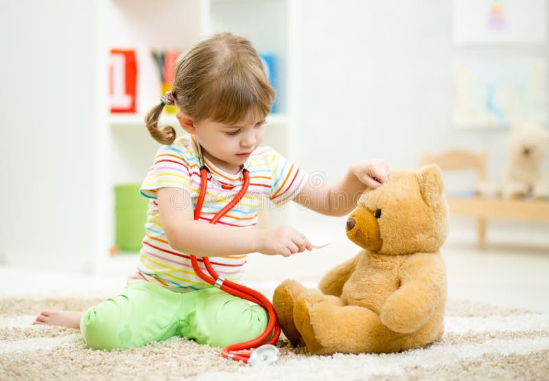 Child girl playing doctor and curing plush toy