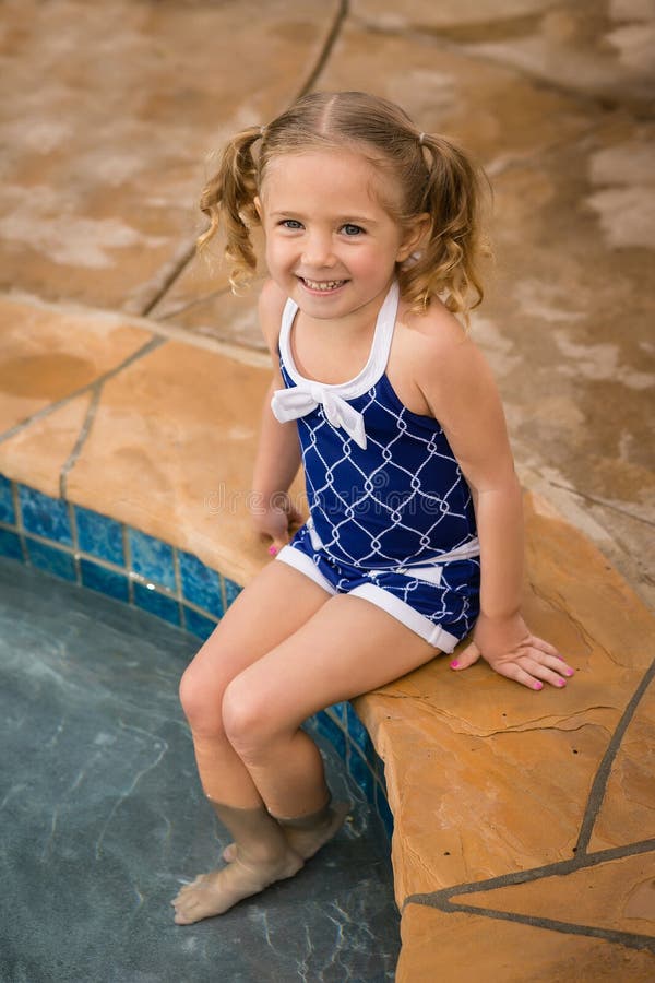 Young female child in blue swim suit sitting on pool steps. Young female child in blue swim suit sitting on pool steps