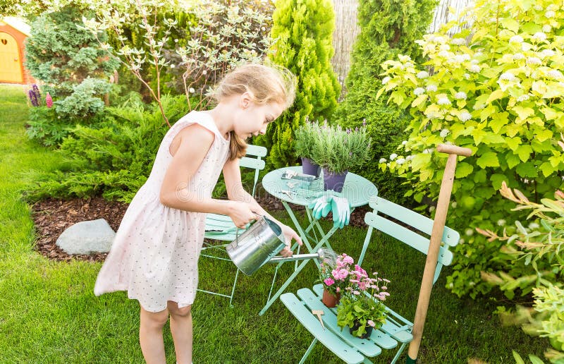 Child girl watering flowers outdoor in a summer garden royalty free stock photography Child girl watering flowers outdoor in a summer garden royalty free stock photography