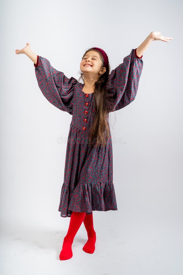 A child in a gray dress with flowers, with red buttons, in red tights, isolated on a white background.