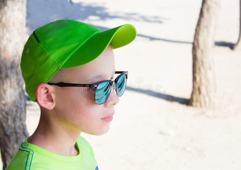 The child in a green baseball cap and sunglasses stock photo
