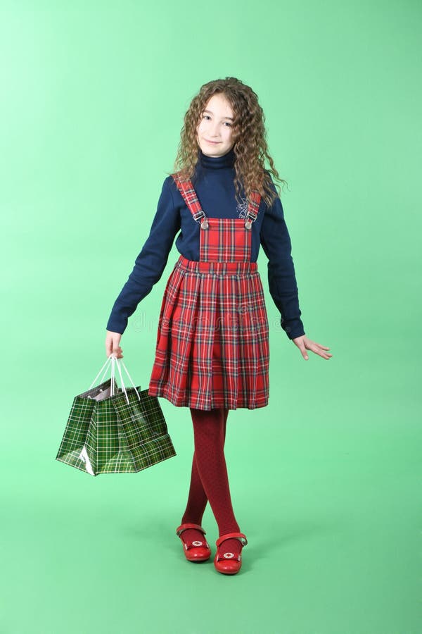 Child with a green packaging checkered texture isolated on green background. Girl likes shopping on sale season. Holiday present, royalty free stock photo Child with a green packaging checkered texture isolated on green background. Girl likes shopping on sale season. Holiday present, royalty free stock photo