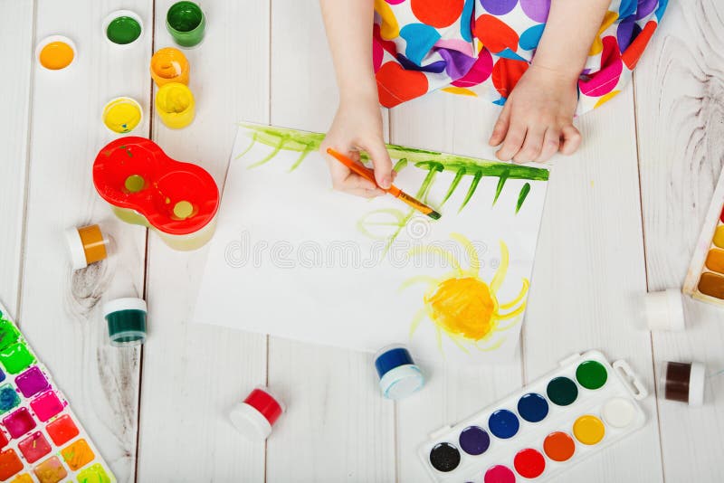 Child hand with brushes drawing on white paper yellow sun. stock photography Child hand with brushes drawing on white paper yellow sun. stock photography