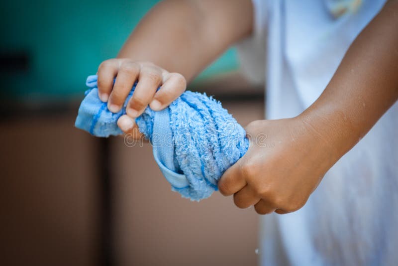 Child hands squeeze wet blue towel