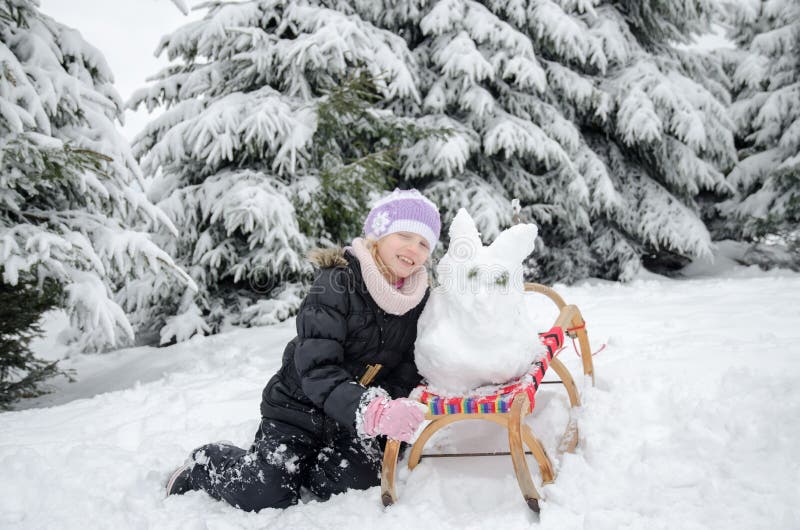 Child having happy winter time with lot of snow and little snowman built in sleight stock photo Child having happy winter time with lot of snow and little snowman built in sleight stock photo