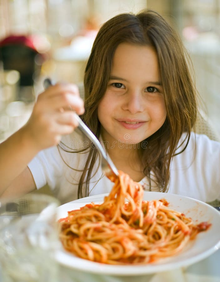 Mladé dievča jesť špagety v reštaurácii.