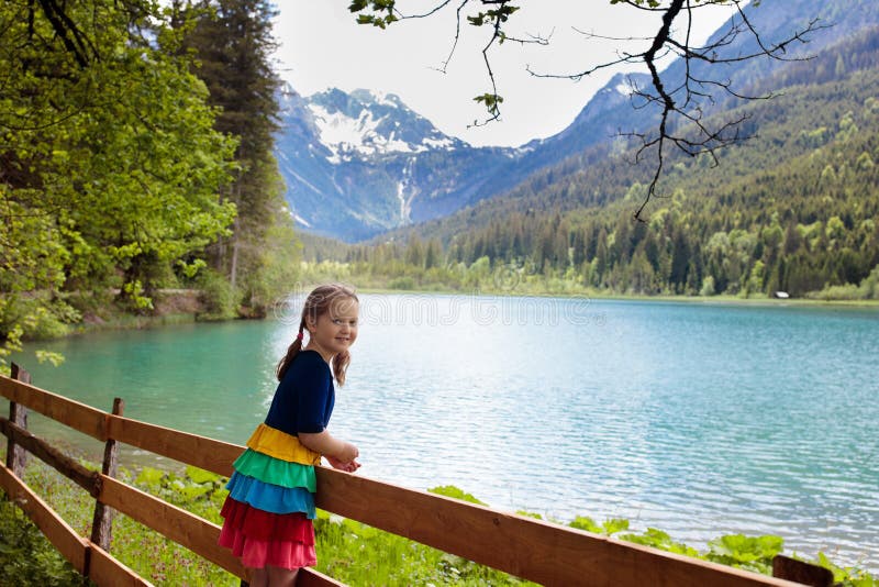 Child hiking in flower field at mountain lake stock photo Child hiking in flower field at mountain lake stock photo