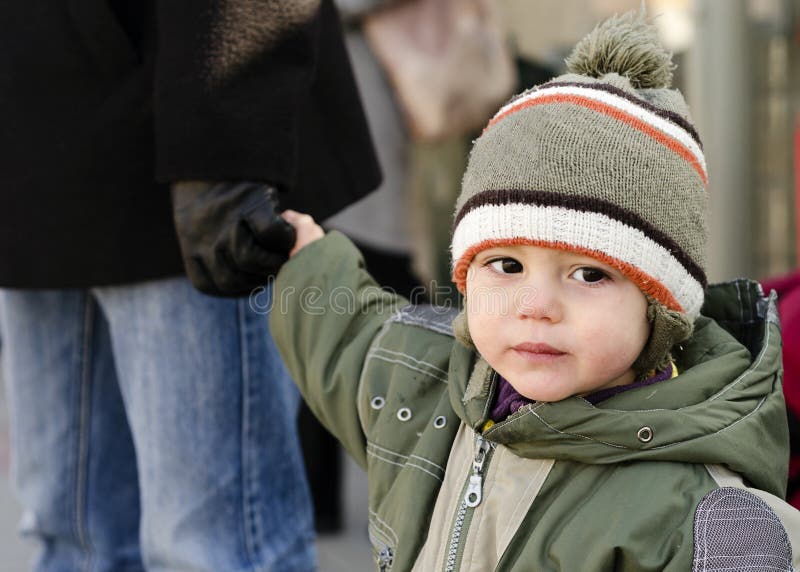 Bambino, bambino, ragazzo o ragazza, che tiene una mano al padre nel freddo inverno.