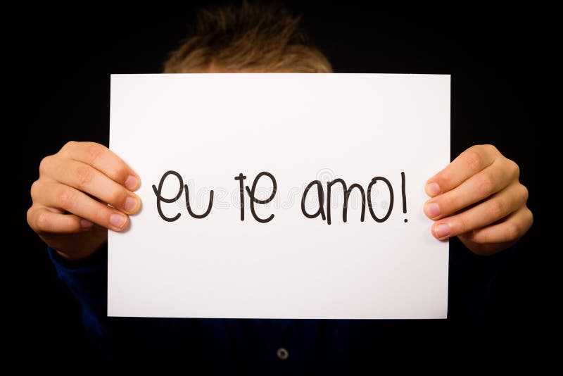 Child holding sign with Portuguese words Eu Te Amo - I Love You