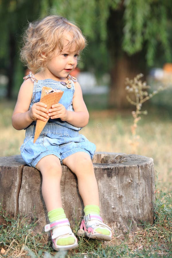 Child with ice-cream sitting on stump