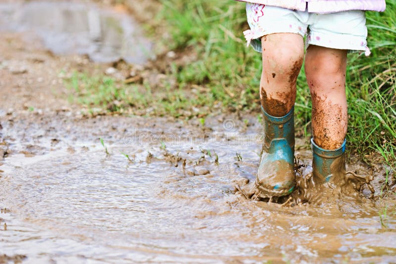 Child's feet stomping in a mud puddle and splashing mud. Child's feet stomping in a mud puddle and splashing mud.