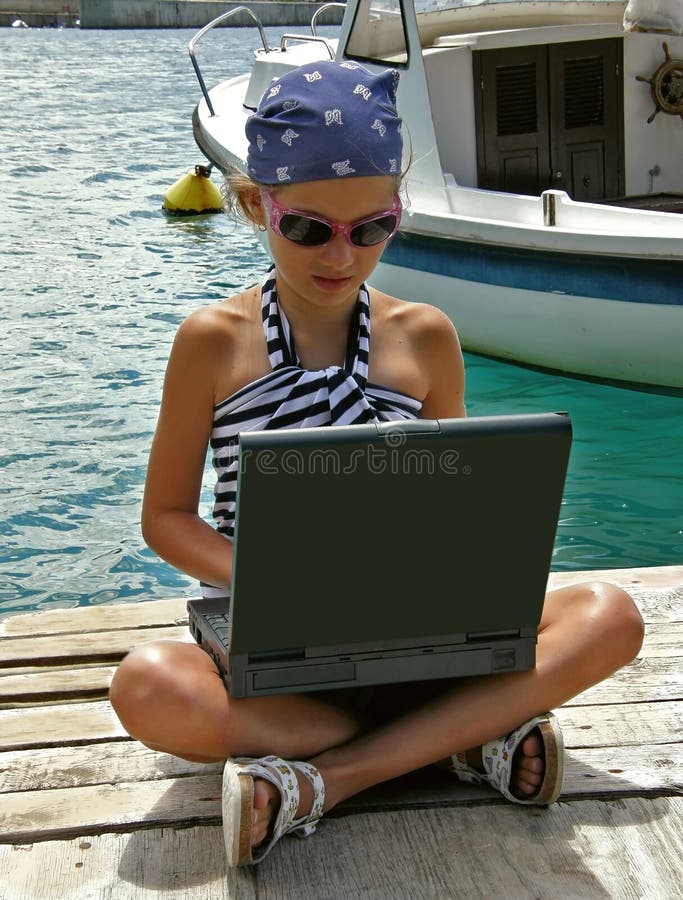 Child with laptop in harbor. A young girl in a sailor dress with laptop at Adriatic sea