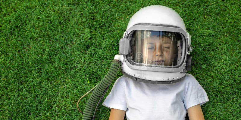 Child Lies On The Grass Wearing An Astronaut`s Helmet And Dreams Of Great Achievements Stock ...