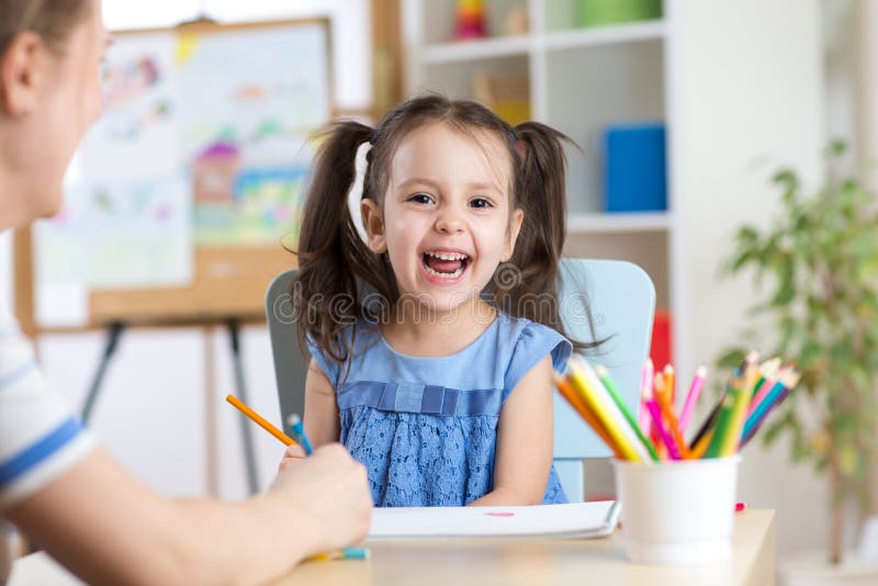 Child little girl laughing, painting colorful pencils at her playtable royalty free stock images Child little girl laughing, painting colorful pencils at her playtable royalty free stock images