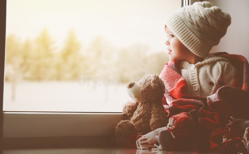 Child little girl with teddy bear at window and looking at wint stock images Child little girl with teddy bear at window and looking at wint stock images
