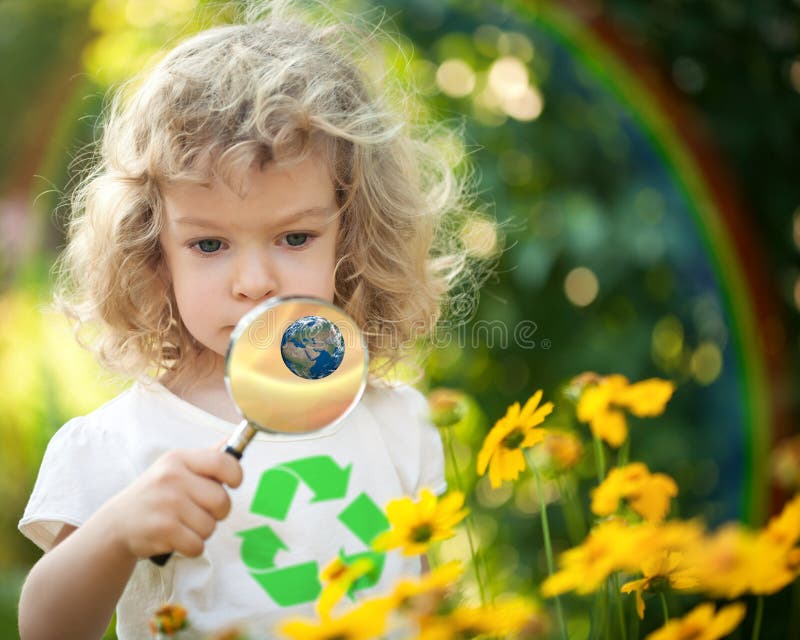 Child with recycle symbol on T-shirt looking at spring flowers against rainbow. Earth day concept. Elements of this image furnished by NASA. Child with recycle symbol on T-shirt looking at spring flowers against rainbow. Earth day concept. Elements of this image furnished by NASA