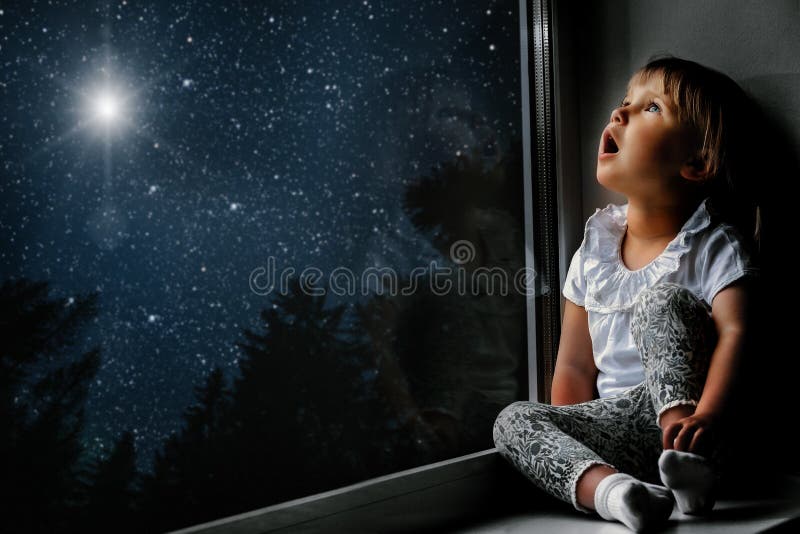 child looks out the window into the night sky