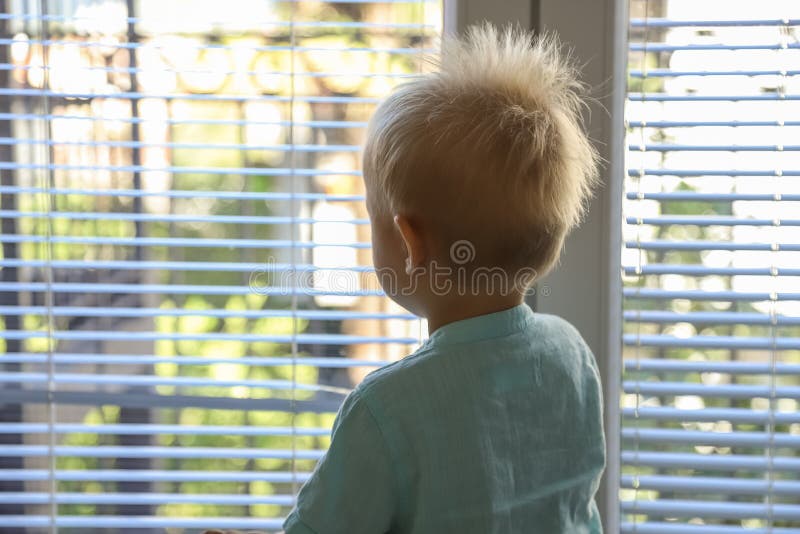 Child looks out the window and waits for the cancellation of quarantine, wants to go outside stock image Child looks out the window and waits for the cancellation of quarantine, wants to go outside stock image